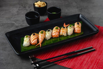 Sushi set of various products on a black stone plate. Blur background and selective focus