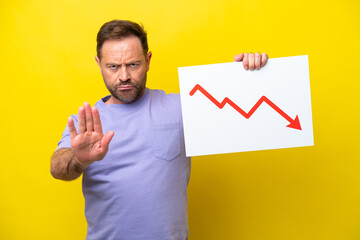 Middle age caucasian man isolated on yellow background holding a sign with a decreasing statistics...
