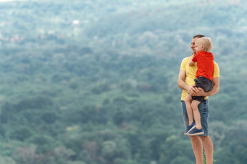 Father holds his son in his arms. Father and son stand on the observation deck and admire the...