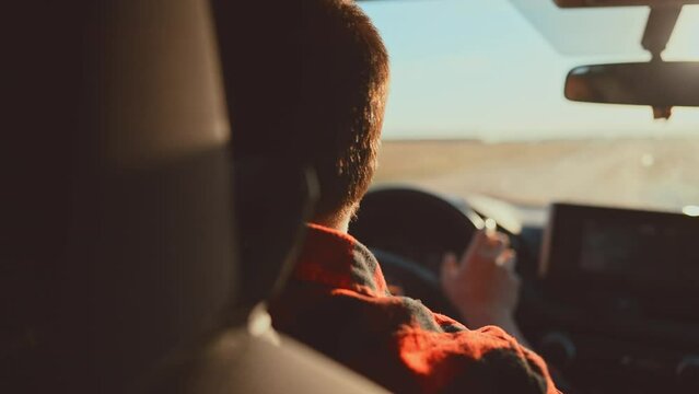 Rear view in saloon auto on male who driving on rural road. Blurred view from front window car and rear view inside mirror. Summer travel by transport outside city on uneven sections bumps and pits.