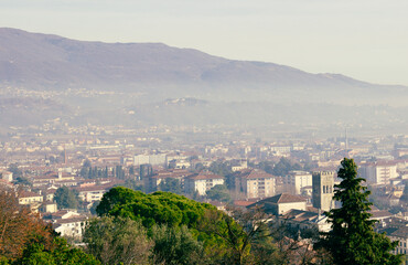 Fototapeta na wymiar Urban landscape. Aerial view of the city of Vittorio Veneto with the mountains in the background. Day with haze.