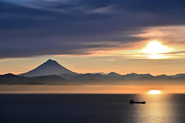 Naklejka na ściany i meble A beautiful harsh sunset against the backdrop of the Vilyuchinsky volcano in Kamchatka 