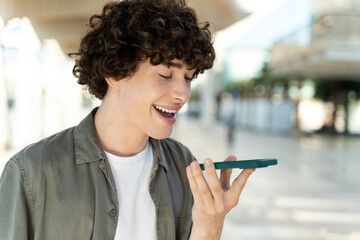 Caucasian man recording voice message via smartphone while walking in city street