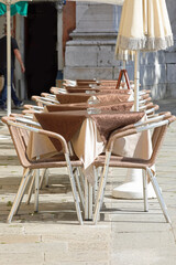 empty chairs and tables in the outdoor cafe without people due to the lockdown