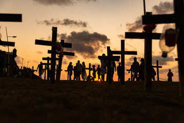 Silhouette of people and crosses fixed on the ground in honor of those killed by covid-19.