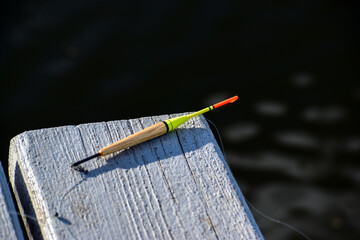 Fishing float with fishing line lies on wooden boards close-up on a dark background