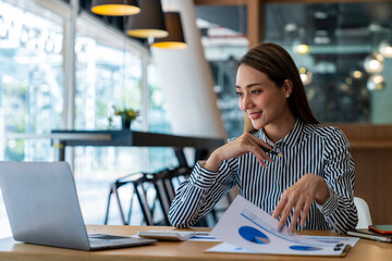 Portrait of beautiful asian woman working financial report with laptop computer at office.