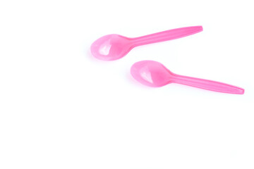Pink plastic spoons on white background