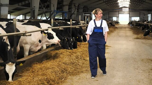 Happy young woman farmer walking in cowshed