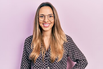 Obraz premium Beautiful hispanic woman wearing casual clothes and glasses looking positive and happy standing and smiling with a confident smile showing teeth