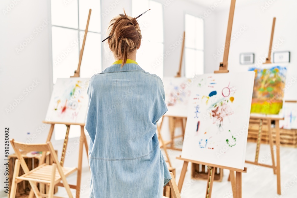 Poster young caucasian girl at art studio standing backwards looking away with crossed arms