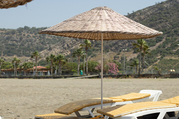 Beautiful beach with umbrellas and sun loungers. A perfect summer vacation destination. Empty beach with mountainous and wooded background, parasols and sun loungers.