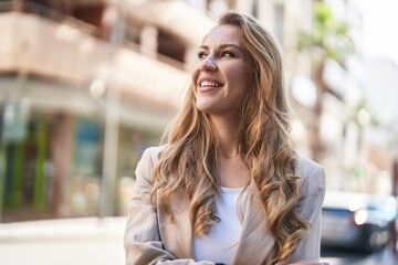 Young blonde woman smiling confident standing with arms crossed gesture at street