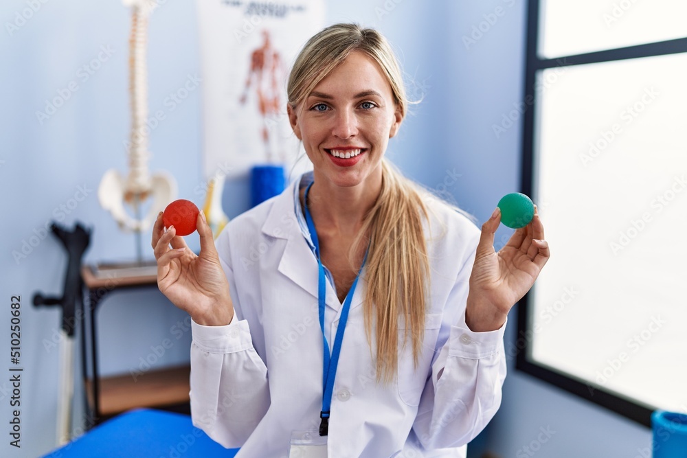 Wall mural Beautiful woman holding strength ball for hand rehabilitation smiling with a happy and cool smile on face. showing teeth.