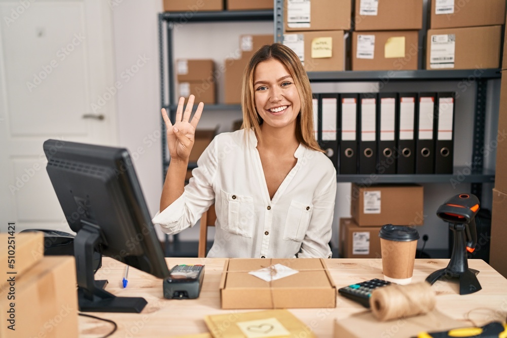 Canvas Prints Young blonde woman working at small business ecommerce showing and pointing up with fingers number four while smiling confident and happy.