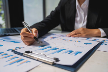 Businesswoman hold graph pens and use a calculator for the company's improvement plan.