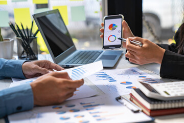 Fototapeta premium Two business people sit down to analyze financial data from earnings graphs showing the company's earnings to be presented at a meeting.