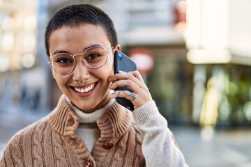 Young hispanic woman with short hair smiling happy speaking on the phone