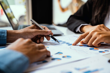 Two business people sit down to analyze financial data from earnings graphs showing the company's earnings to be presented at a meeting.