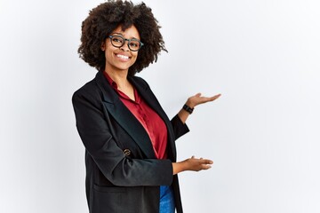 African american woman with afro hair wearing business jacket and glasses inviting to enter smiling...