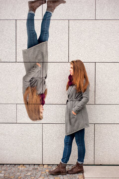 Teenager Girl Leaning Against A Wall With Picture Of Her On The Wall Liek A Concept When One Feels Upside Down With Mood 