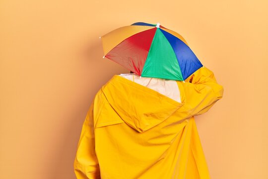 Young african american man wearing yellow raincoat backwards thinking about doubt with hand on head