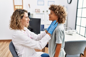 Mother and son smiling confident examining thoat at clinic
