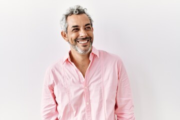 Middle age hispanic man standing over isolated background looking away to side with smile on face,...
