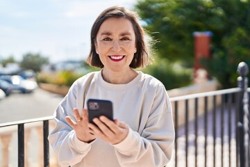 Middle age woman smiling confident using smartphone at park