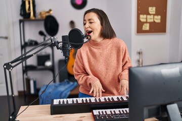 Middle age woman musician singing song playing piano at music studio