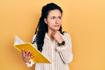 Young hispanic woman with curly hair holding book touching painful neck, sore throat for flu, clod...
