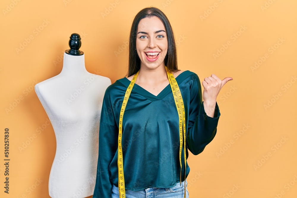 Sticker beautiful woman with blue eyes standing by manikin pointing thumb up to the side smiling happy with 