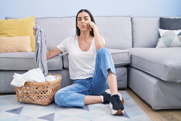 Young brunette woman doing laundry at home looking at the camera blowing a kiss being lovely and sexy. love expression.