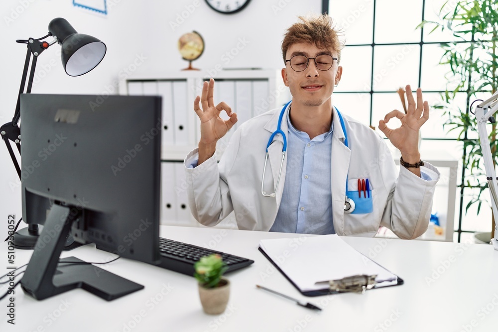 Sticker Young caucasian doctor man working at the clinic relax and smiling with eyes closed doing meditation gesture with fingers. yoga concept.