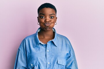 Young african american woman wearing casual clothes puffing cheeks with funny face. mouth inflated...