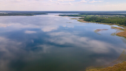 Aerial view of lake with sky reflection. Blue lake and green forest. Image for design. Space for text.
