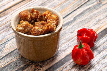 .Pork crackling portion served in a pot on the wooden table
