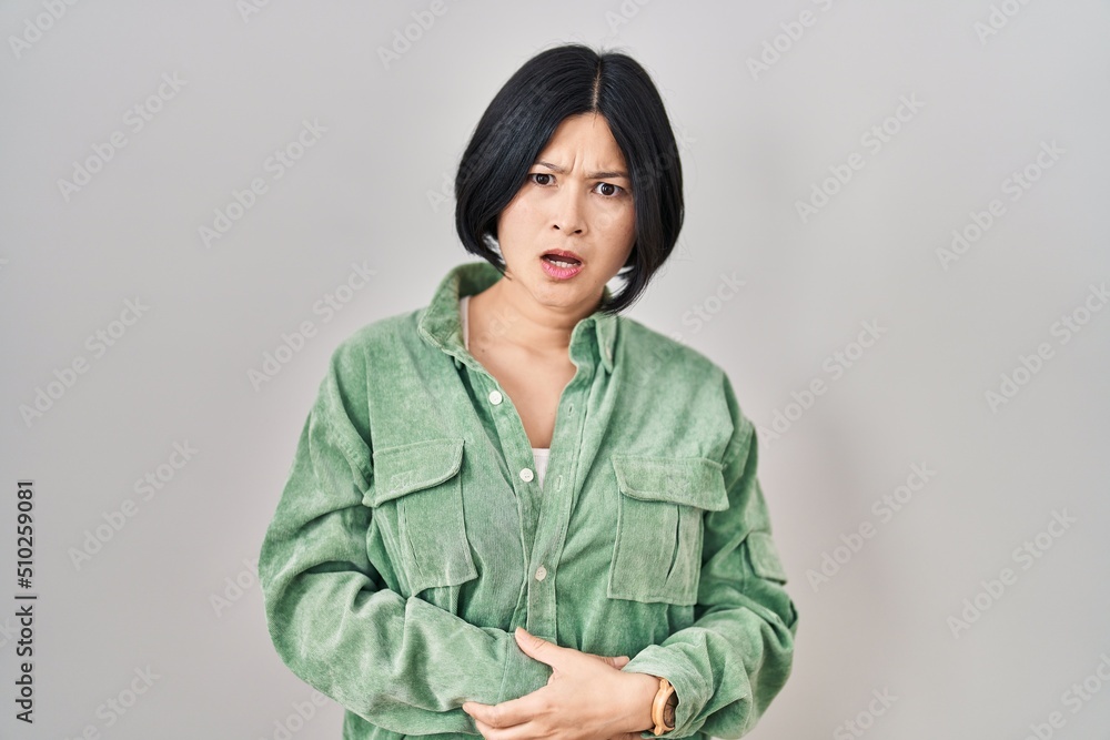 Sticker young asian woman standing over white background in shock face, looking skeptical and sarcastic, sur