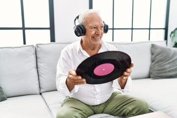 Senior man listening to music holding vinyl disc at home