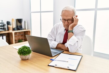 Senior man working at the office using computer laptop thinking looking tired and bored with depression problems with crossed arms.