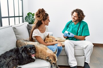 Man and woman wearing veterinarian uniform examining dog at home
