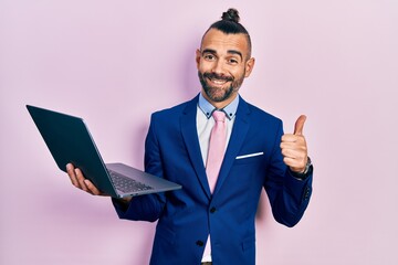 Young hispanic man working using computer laptop smiling happy and positive, thumb up doing excellent and approval sign