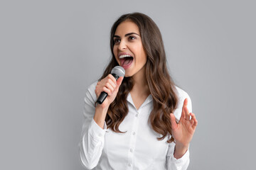 Young excited woman singing a song with a microphone, presenting an event or having a party. Happy...
