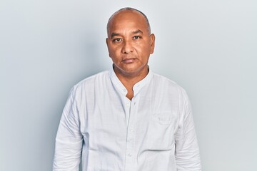 Middle age latin man wearing casual clothes relaxed with serious expression on face. simple and natural looking at the camera. - obrazy, fototapety, plakaty