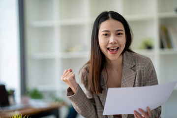 excited business woman reading good news in paper letter She was promoted and received an additional yearly bonus.