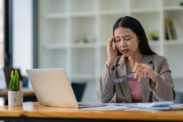 Business Woman Having Headache While Working Using Laptop Computer. Stressed And Depressed Girl Touching Her Head, Feeling Pain While Sitting At Wooden Table, Work Failure Concept