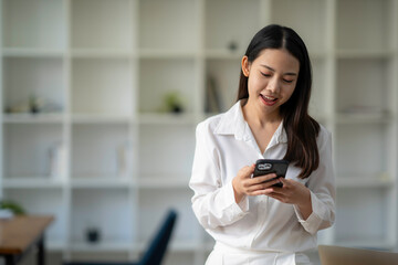 Attractive looking Asian business woman using a smartphone. to wipe email and work online via mobile
