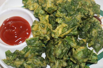 Homemade delicious palak pakoda or pakora also known as Spinach Firtters, served with ketchup or...