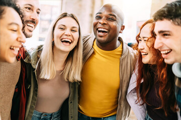 Multiracial group of friends having fun together on city street - Millenial people laughing hugging outside - Friendship concept with guys and girls enjoying hanging outside