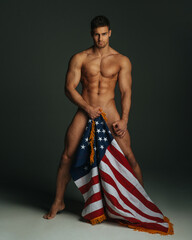 Sexy fitness male model with American flag covering his naked body - obrazy, fototapety, plakaty